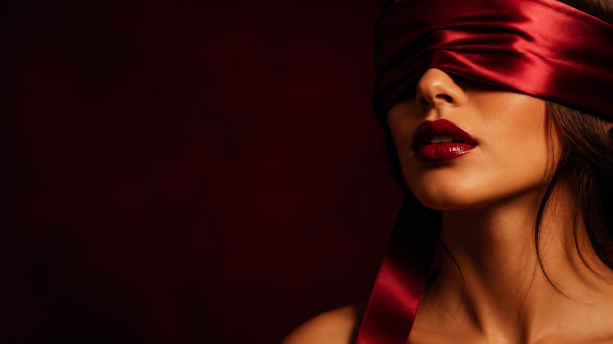 A spicy romance book open on silk sheets by candlelight